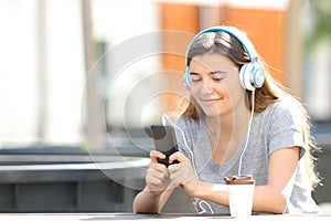 Teenage girl listening to music using phone in a park