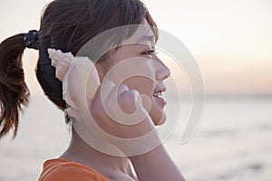 Teenage girl listening to seashell, profile