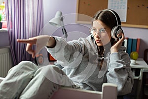 A teenage girl listens to music and gestures with her hands. Wireless headphones.