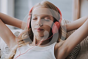 Teenage girl listens to music on headphones, closing eyes.
