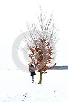 Teenage girl by lonely tree in snow