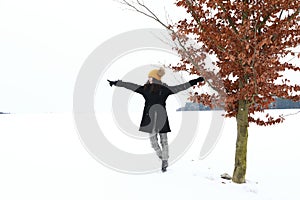 Teenage girl by lonely tree in snow