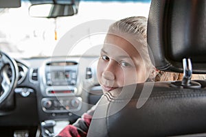 Teenage girl looking back from passenger front seat of car, Caucasian child