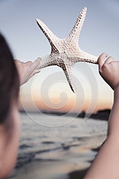 Teenage girl looking and holding up starfish