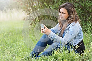 Teenage girl is looking at the smart phone outdoors