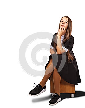 Teenage girl looking up with interest while sitting on a chair