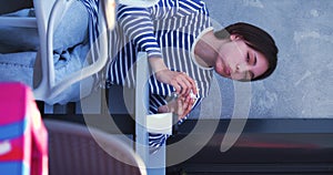 Teenage girl looks at her burger and takes a big bite while she sitting at sidewalk cafe.