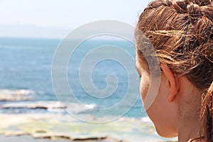 A teenage girl looks at the sea below