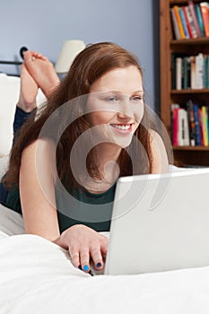 Teenage Girl Lying On Bed Using Laptop