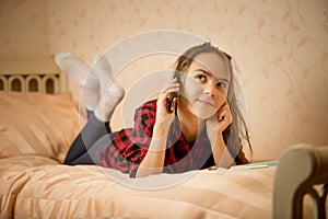 Teenage girl lying in bedroom and talking by phone