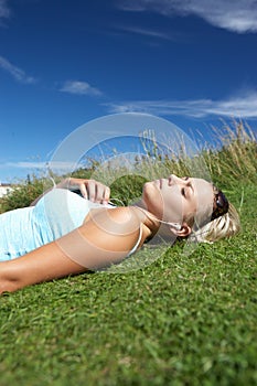 Teenage girl lying on grass with mp3 player