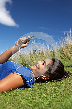 Teenage girl lying on grass with mp3 player