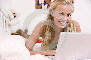 Teenage Girl Lying On Her Bed Using Laptop