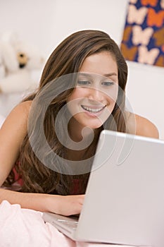 Teenage Girl Lying On Her Bed Using Laptop