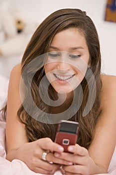 Teenage Girl Lying On Her Bed Using Mobile Phone