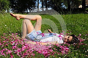 Teenage girl lying on petals in grass