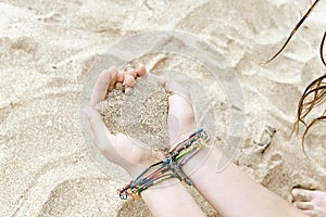 Teenage girl making a heart with her hands and sand