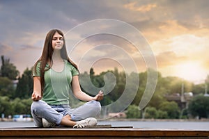 Teenage girl meditating near rive