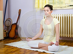 Teenage girl meditating in yoga pose in her room