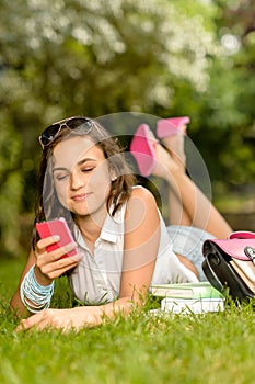 Teenage girl with mobile phone lying grass
