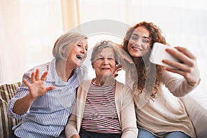 A teenage girl, mother and grandmother with smartphone at home.