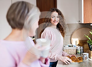 A teenage girl with mother in the kitchen at home.