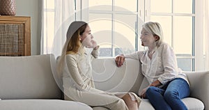 Teenage girl and mother talking resting seated on sofa