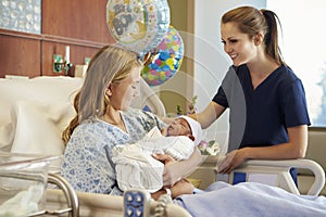 Teenage Girl With Nurse Holding Newborn Baby In Hospital