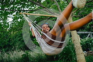 Teenage girl outdoors in garden, swinging on swing, having fun during warm summer evening.