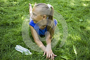 Teenage girl in a park lying on green grass with bottle of wate