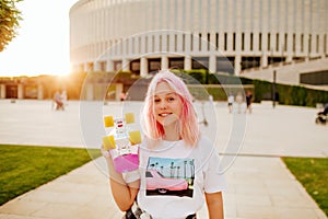 Teenage girl with pink hair holds longboard and smiling