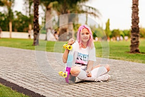 Teenage girl with pink hair holds longboard and smiling