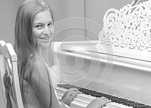 A teenage girl is playing on a white grand piano.