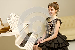 A teenage girl is playing on a white grand piano.