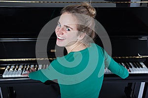 Teenage girl plays piano in green shirt