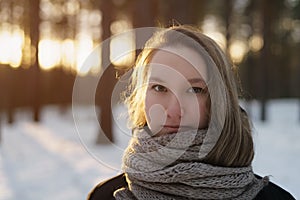 Teenage girl portrait in winter pine forest is sunset