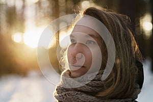 Teenage girl portrait in winter pine forest is sunset