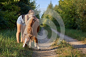 Teenage girl posing with a little horse on the country road