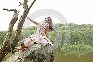 Teenage girl posing on rock above river