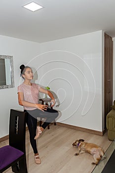 Teenage girl practicing ballet in her living room next to her dog