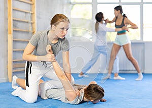 Teenage girl practicing painful armlock in sparring during self defense class