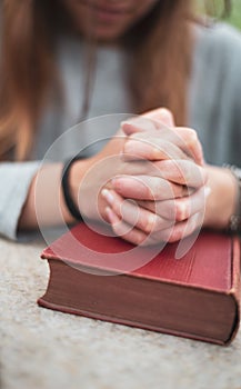 Teenage girl praying at home , hands on bible. concept of faith & hope