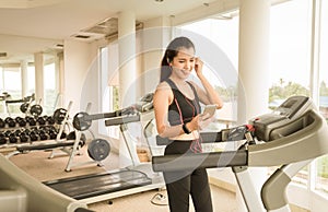 Teenage girl prepare for exercise on running machine choose music before start