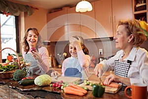 Teenage girl preparing food helping her mother and grandmother in kitchen