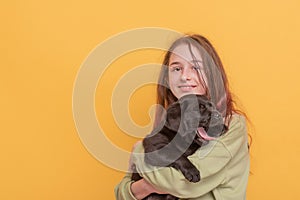 A teenage girl with a puppy. A girl with a black labrador retriever on a yellow background