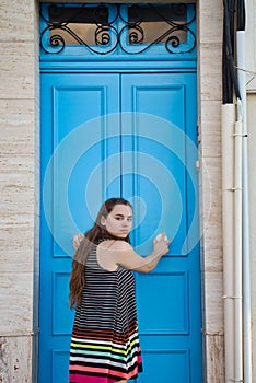 Teenage girl pushing a blue door