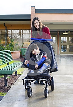 Teenage girl pushing disabled boy in wheelchair