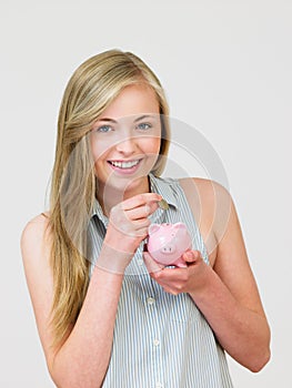 Teenage Girl Putting Money Into Piggy Bank