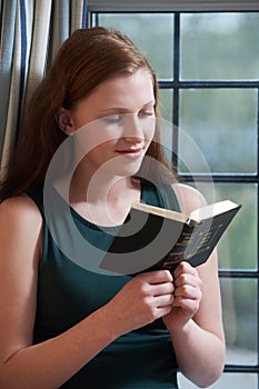 Teenage Girl Reading Her Bible At Home