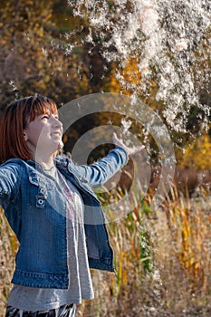 A teenage girl with red hair throws up fluff from a cattail and he falls down.